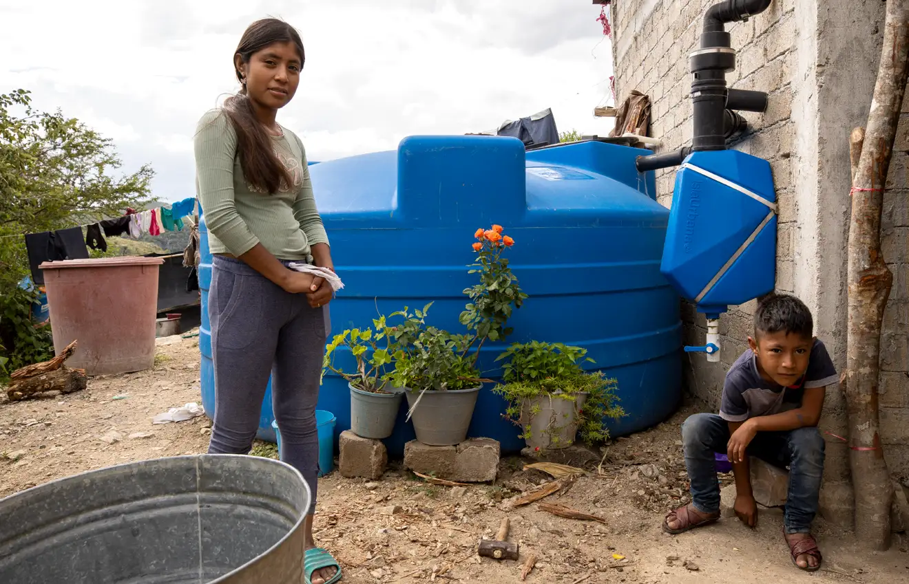 Agua Vida-Brenda-y-Alexis-mobile Agua Vida. Two Kids, Brenda and Alexis next to a Rainwater harvesting system.