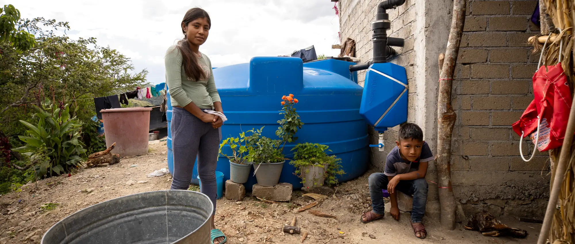 Agua Vida-Brenda-y-Alexis Agua Vida. Two Kids, Brenda and Alexis next to a Rainwater harvesting system.