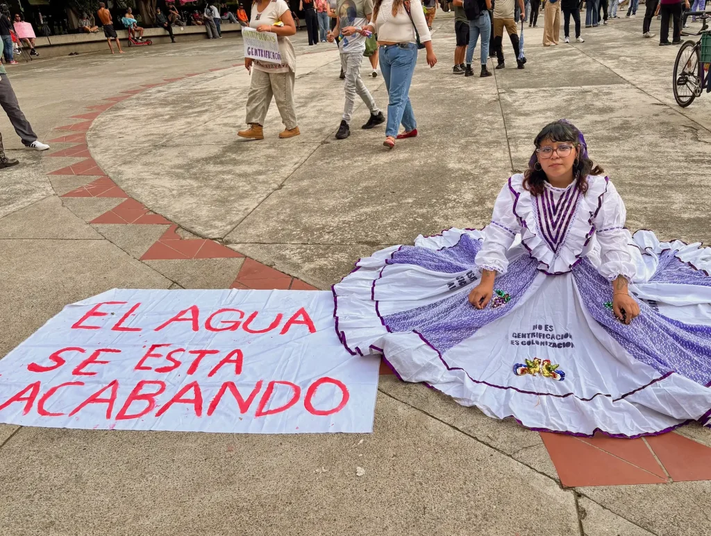 Mexico City. A girl with a traditional Mexican dress sitting on the floor next to a big poster with the legend: "The water is running out".